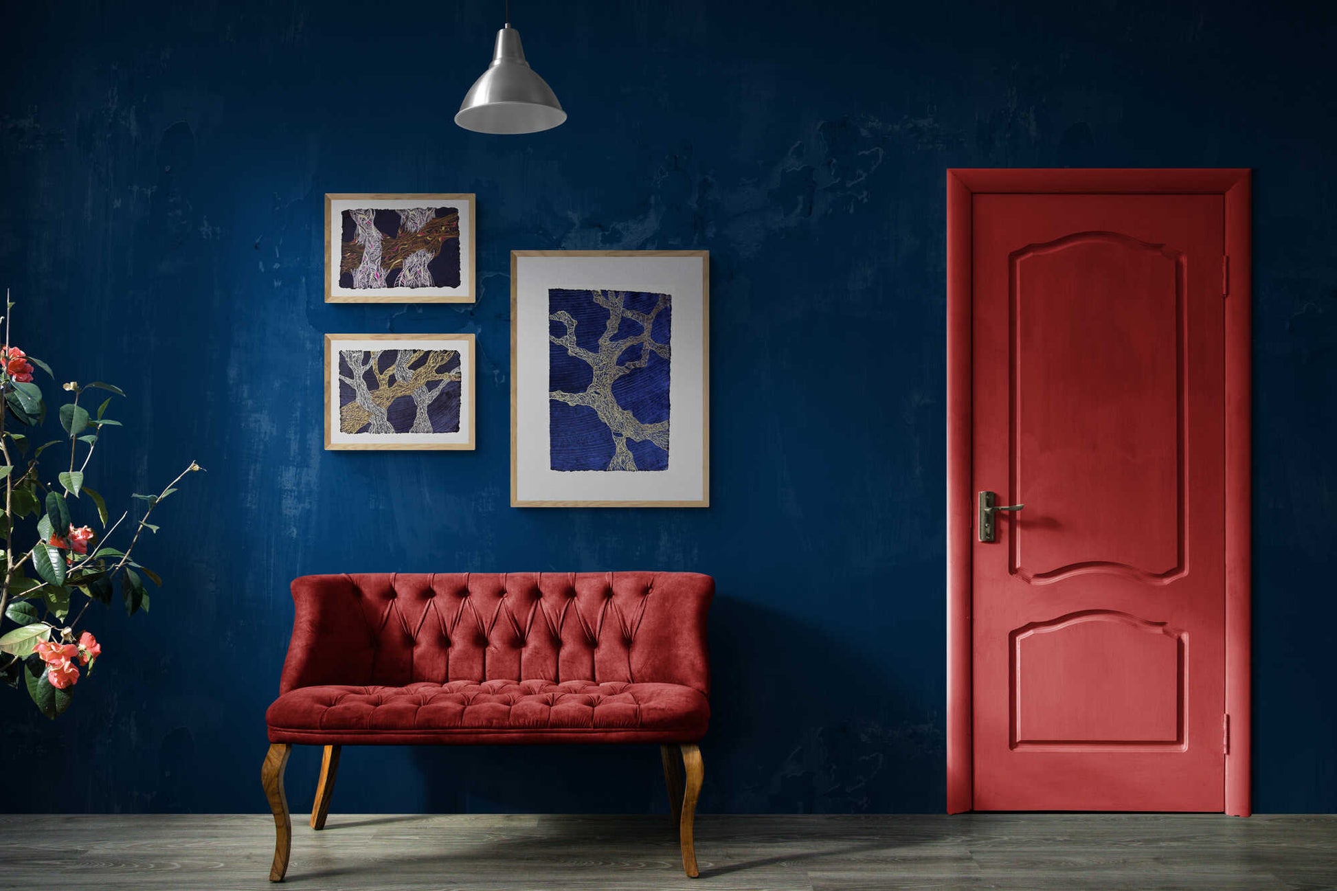 3 of the Turia series drawings framed and hanging on a dark blue wall above a red sofa, with a red door on the right. 