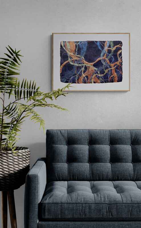 The painting inspired by the ficus trees in Valencia in a wooden frame, hanging on a white wall above a grey sofa, with a leafy plant in a raised vase on the left.